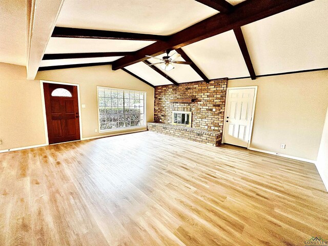 unfurnished living room featuring lofted ceiling with beams, a brick fireplace, ceiling fan, and light hardwood / wood-style flooring