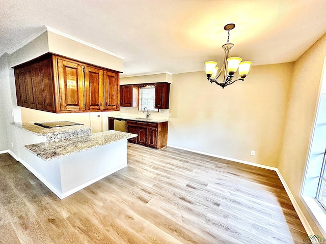 kitchen featuring decorative light fixtures, sink, dishwashing machine, light hardwood / wood-style floors, and an inviting chandelier