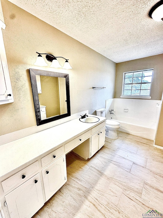 bathroom with vanity, a washtub, a textured ceiling, and toilet