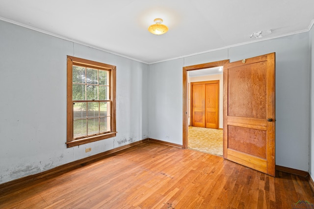 empty room with wood-type flooring and ornamental molding