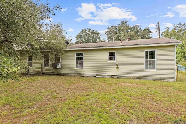 rear view of house featuring cooling unit and a lawn