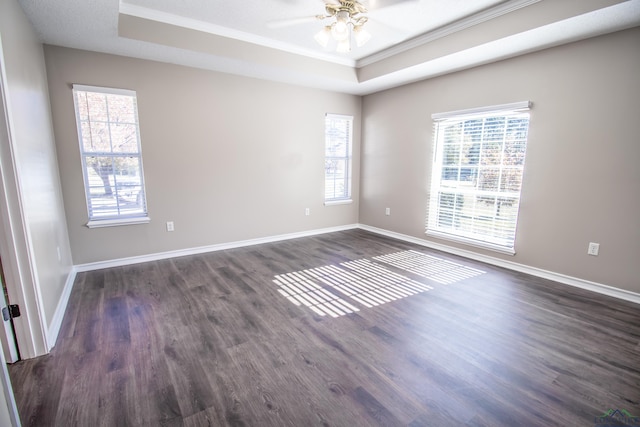 empty room featuring a raised ceiling, ceiling fan, and dark wood-type flooring