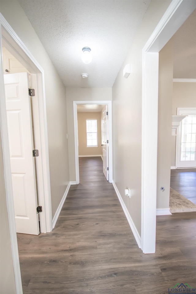 corridor with a textured ceiling and dark hardwood / wood-style floors