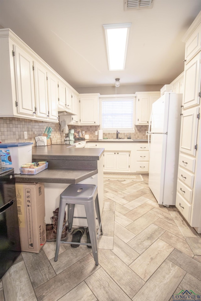 kitchen featuring white cabinets, white refrigerator, kitchen peninsula, and tasteful backsplash