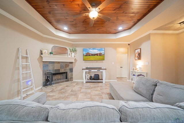 living room featuring ceiling fan, wood ceiling, a tile fireplace, and a tray ceiling