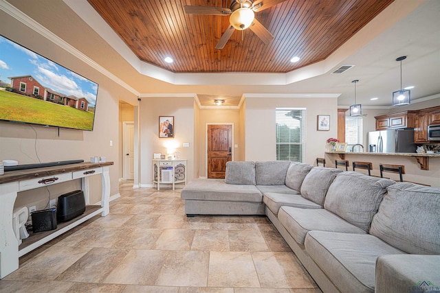 living room with a raised ceiling, ceiling fan, ornamental molding, and wood ceiling