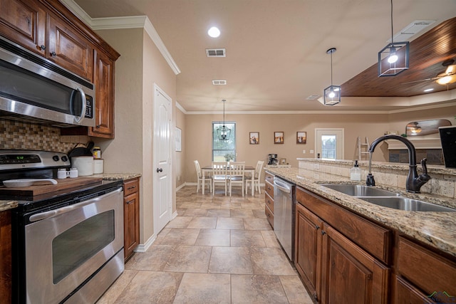 kitchen featuring light stone countertops, sink, crown molding, pendant lighting, and appliances with stainless steel finishes