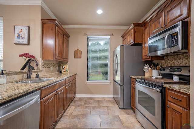 kitchen featuring appliances with stainless steel finishes, tasteful backsplash, light stone counters, ornamental molding, and sink