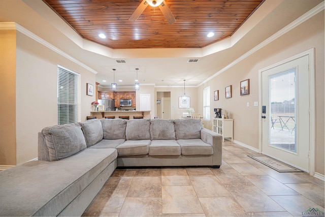 living room with a tray ceiling, ceiling fan, crown molding, and wood ceiling