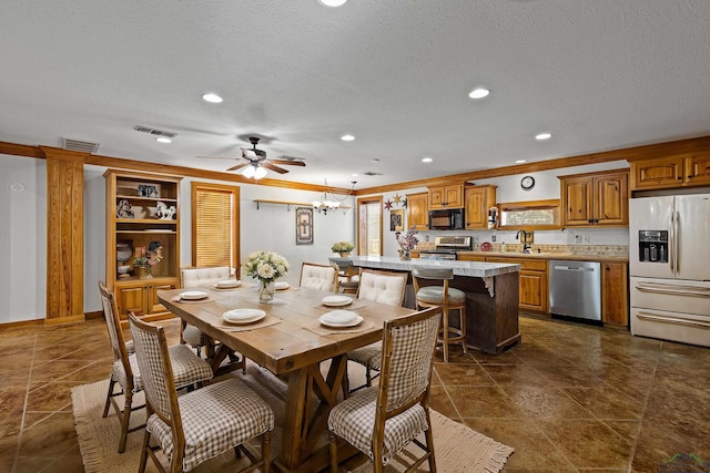 dining space with ceiling fan with notable chandelier, a textured ceiling, ornamental molding, and sink