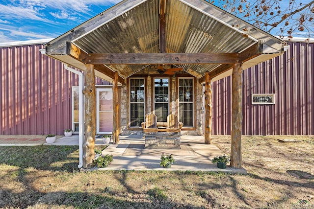 view of exterior entry with a lawn and a patio