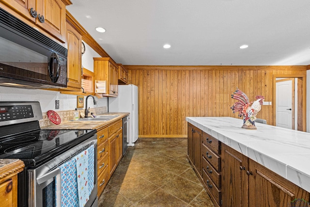 kitchen with wood walls, appliances with stainless steel finishes, ornamental molding, and sink