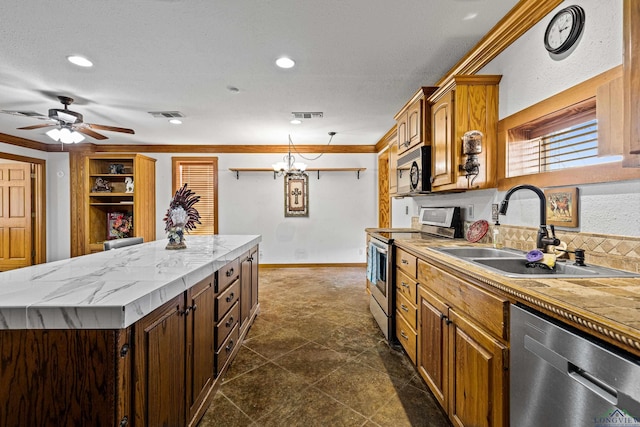 kitchen with stainless steel appliances, a kitchen island, backsplash, ornamental molding, and sink