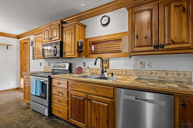 kitchen with sink, stainless steel appliances, ornamental molding, and a textured ceiling