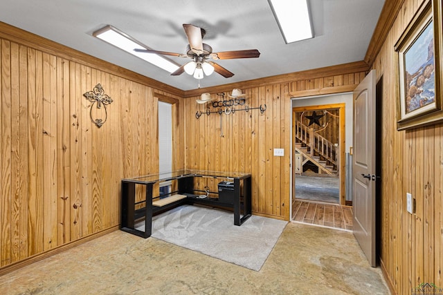 carpeted home office featuring ornamental molding, wood walls, and ceiling fan