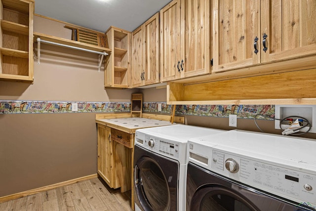 clothes washing area with cabinets, light hardwood / wood-style flooring, and washing machine and dryer