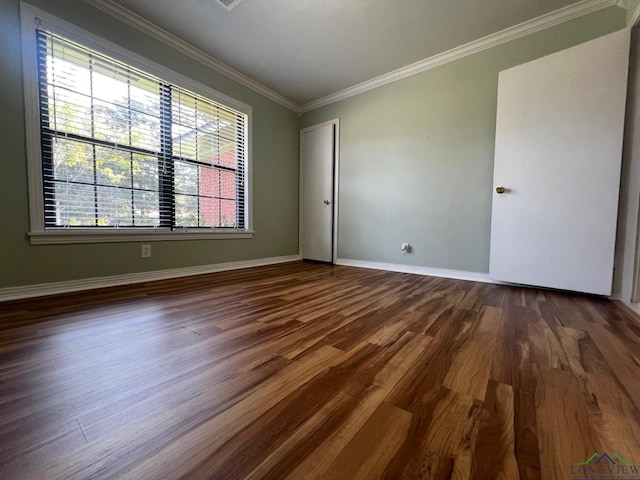 empty room featuring dark wood-type flooring and ornamental molding