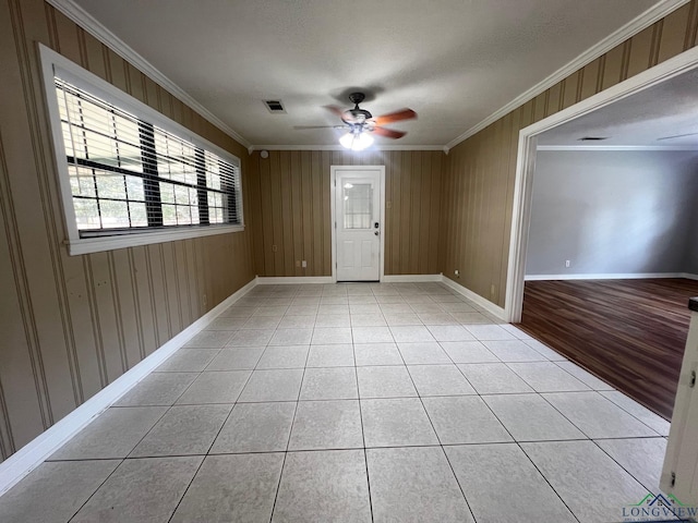 tiled empty room featuring ceiling fan, ornamental molding, and a textured ceiling