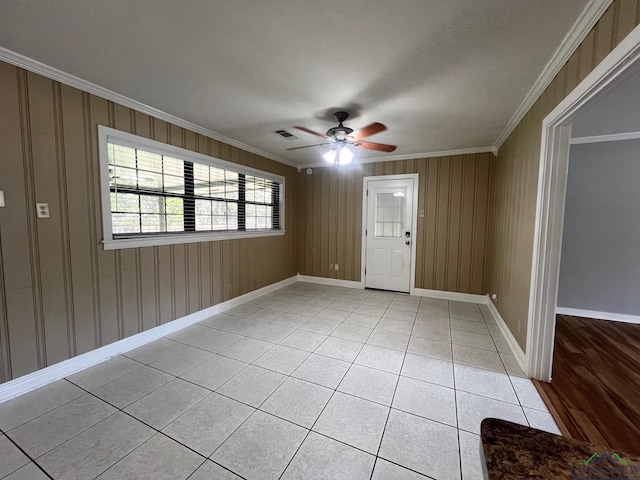 spare room with crown molding, light tile patterned floors, and ceiling fan