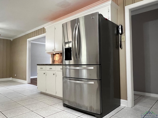 kitchen with white cabinets, stainless steel fridge, ornamental molding, and light tile patterned floors