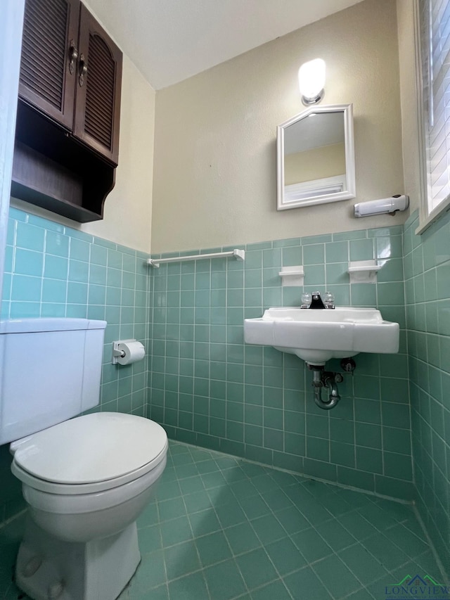 bathroom featuring tile patterned floors, sink, toilet, and tile walls