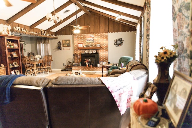 living room featuring vaulted ceiling with beams, ceiling fan with notable chandelier, and a brick fireplace