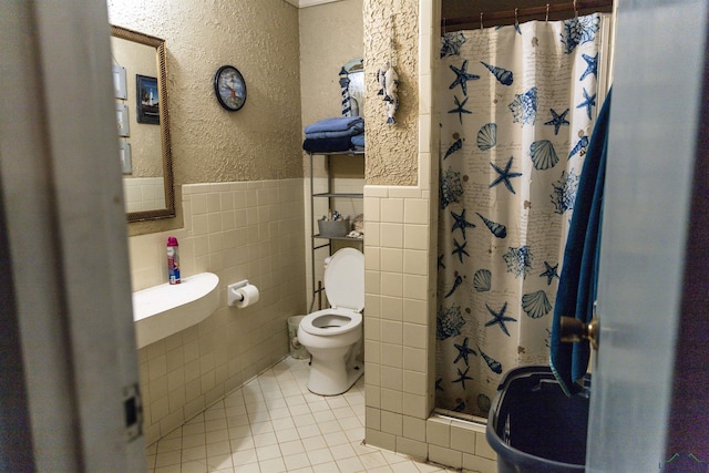 bathroom with tile patterned flooring, a shower with curtain, toilet, and tile walls