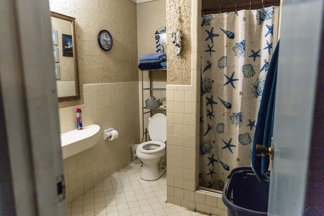 920 Deer Cove Rd, Avinger, TX 75630 - bathroom featuring tile walls, a shower stall, tile patterned flooring, a textured wall, and wainscoting