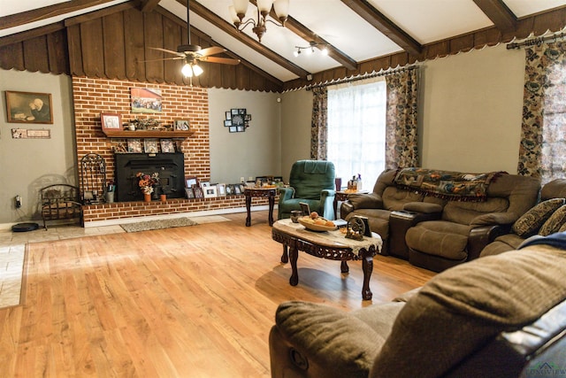 living room featuring ceiling fan, light hardwood / wood-style flooring, lofted ceiling with beams, and a brick fireplace