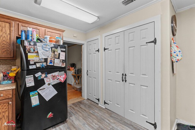office space featuring light wood-style floors, crown molding, and visible vents