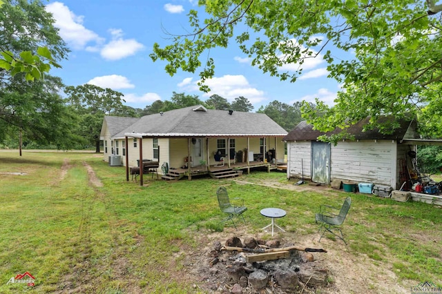 rear view of house featuring central AC, a storage shed, a wooden deck, an outbuilding, and a yard