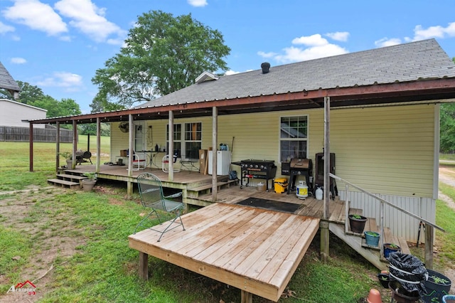 rear view of house featuring a lawn, fence, roof with shingles, and a deck