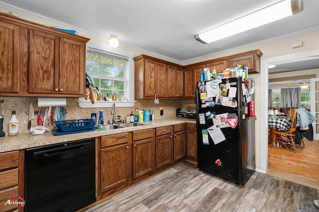 kitchen with decorative backsplash, light wood-type flooring, a sink, light countertops, and black appliances