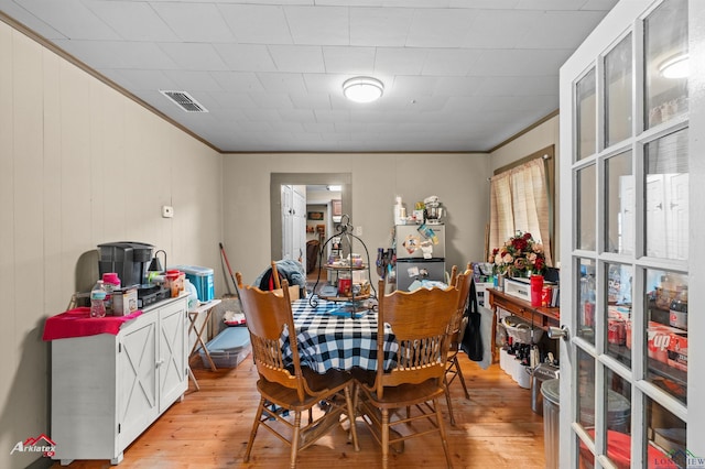 dining area featuring visible vents, ornamental molding, and light wood-style flooring