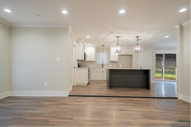 kitchen featuring white cabinetry, sink, hanging light fixtures, crown molding, and light hardwood / wood-style floors