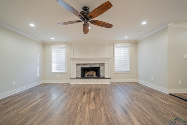 unfurnished living room featuring a stone fireplace, ceiling fan, dark hardwood / wood-style flooring, and ornamental molding