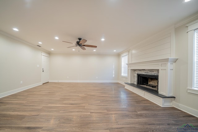 unfurnished living room featuring ceiling fan, a fireplace, ornamental molding, and hardwood / wood-style flooring