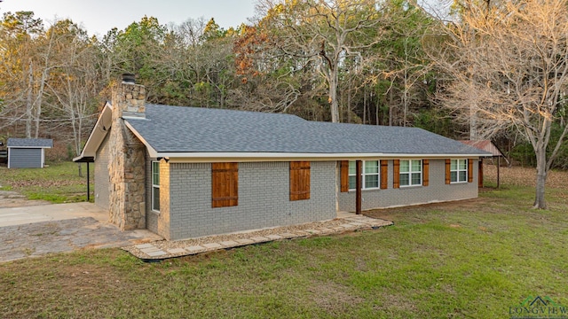 ranch-style house featuring a storage unit and a front lawn