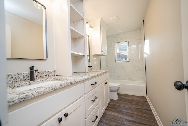 full bathroom featuring tiled shower / bath, vanity, wood-type flooring, and toilet