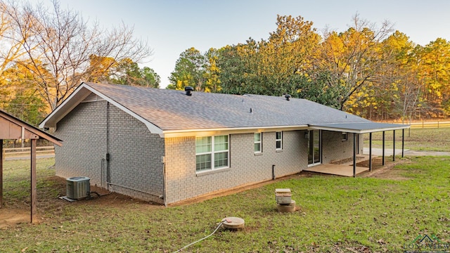 back of property with central AC unit, a patio area, and a lawn