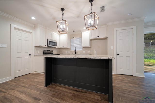 kitchen with white cabinets, appliances with stainless steel finishes, a kitchen island, and pendant lighting