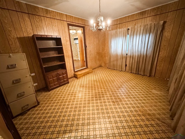 unfurnished dining area featuring a chandelier, ornamental molding, and wood walls