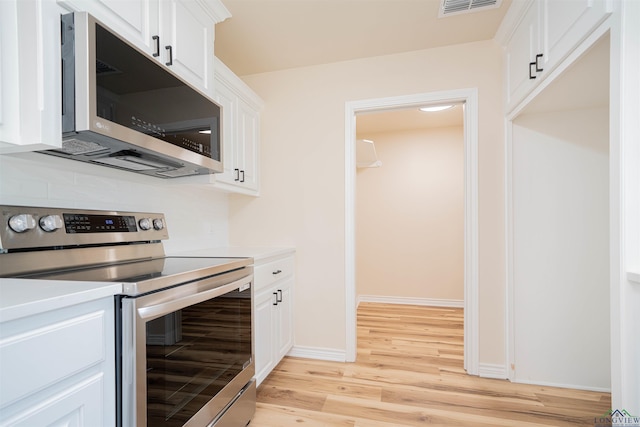 3603 Stracener Rd, Longview, TX 75605 - kitchen featuring appliances with stainless steel finishes, light wood-style floors, backsplash, and white cabinetry