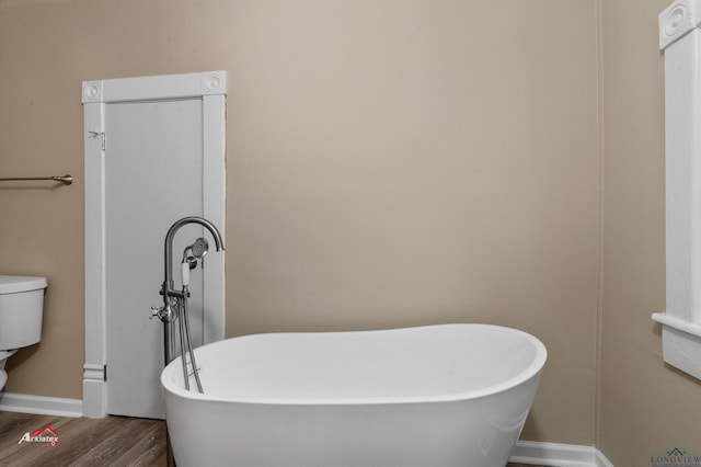 bathroom with hardwood / wood-style floors, toilet, and a bathtub