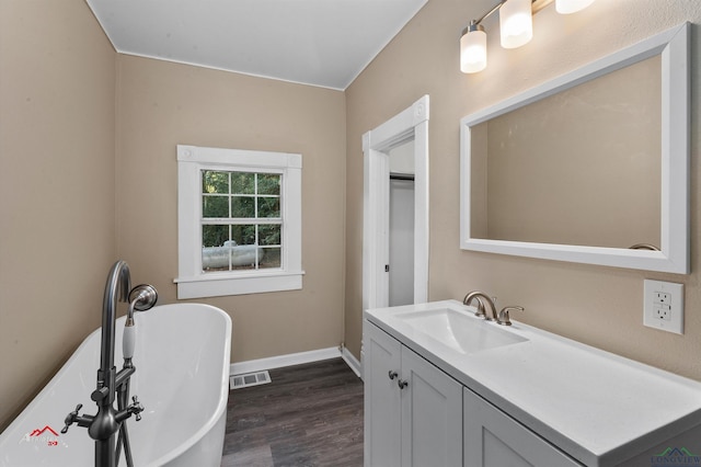 bathroom with a bath, hardwood / wood-style floors, and vanity