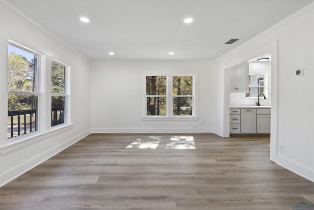 unfurnished dining area with crown molding, sink, and light hardwood / wood-style floors