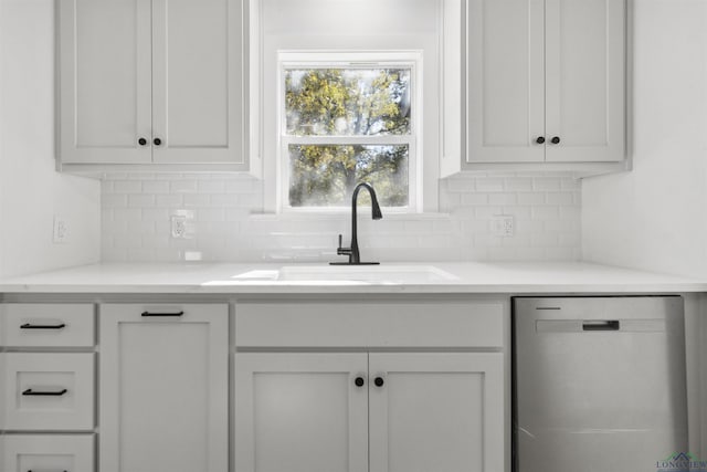 kitchen with tasteful backsplash, white cabinetry, sink, and stainless steel dishwasher