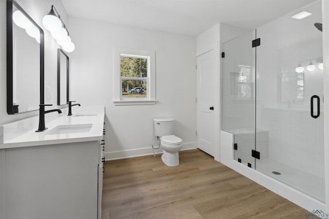 bathroom with toilet, vanity, a shower with door, and hardwood / wood-style flooring