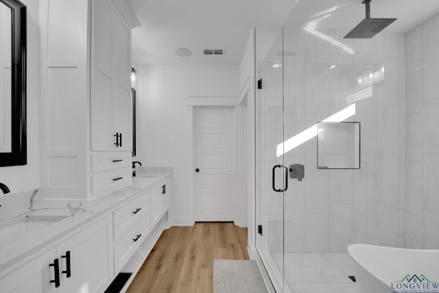 bathroom featuring hardwood / wood-style flooring, plus walk in shower, and vanity