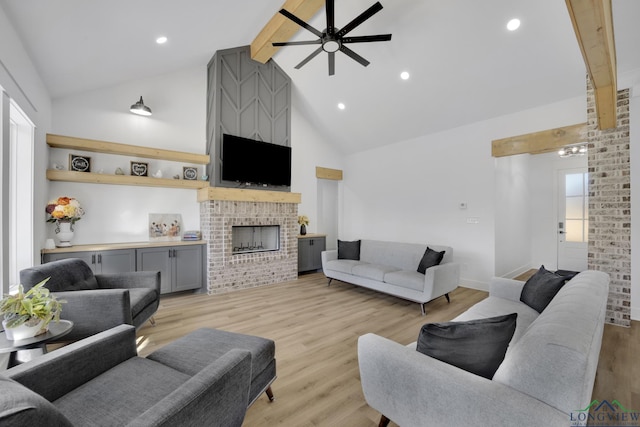 living room featuring beam ceiling, high vaulted ceiling, ceiling fan, a fireplace, and light hardwood / wood-style floors